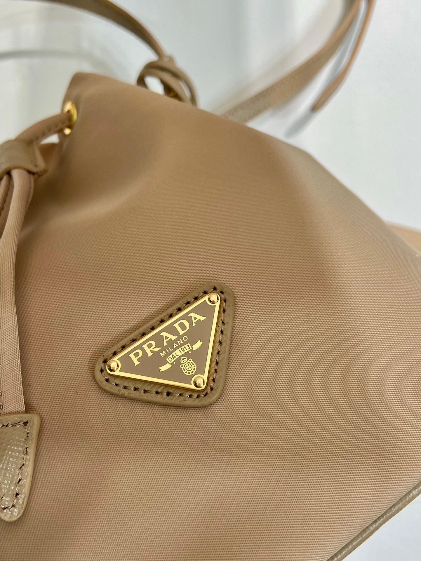 SAC SEAU 19 EN RE-NYLON BEIGE ET POIGNÉE EN CUIR SAFFIANO