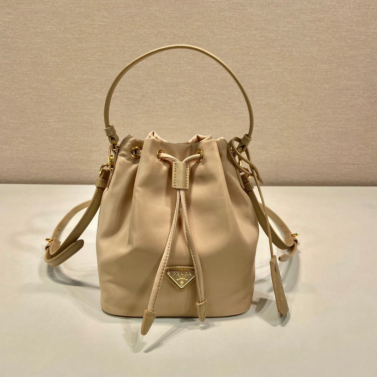 SAC SEAU 19 EN RE-NYLON BEIGE ET POIGNÉE EN CUIR SAFFIANO