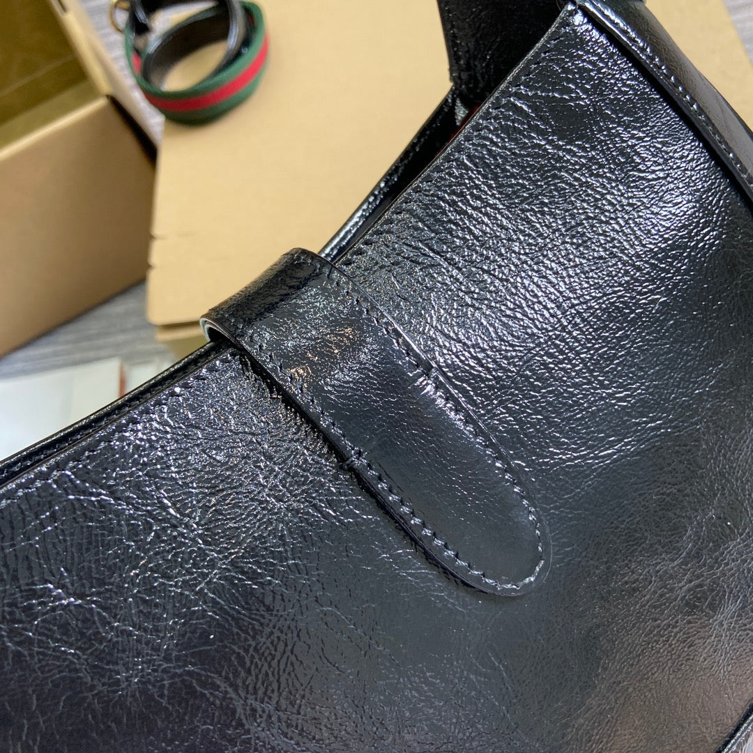 Petit sac bandoulière Jackie 27 en cuir de veau laqué craquelé noir, matériel doré 