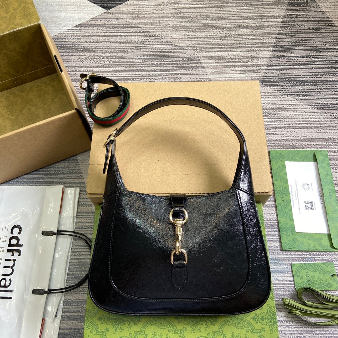 Petit sac bandoulière Jackie 27 en cuir de veau laqué craquelé noir, matériel doré 
