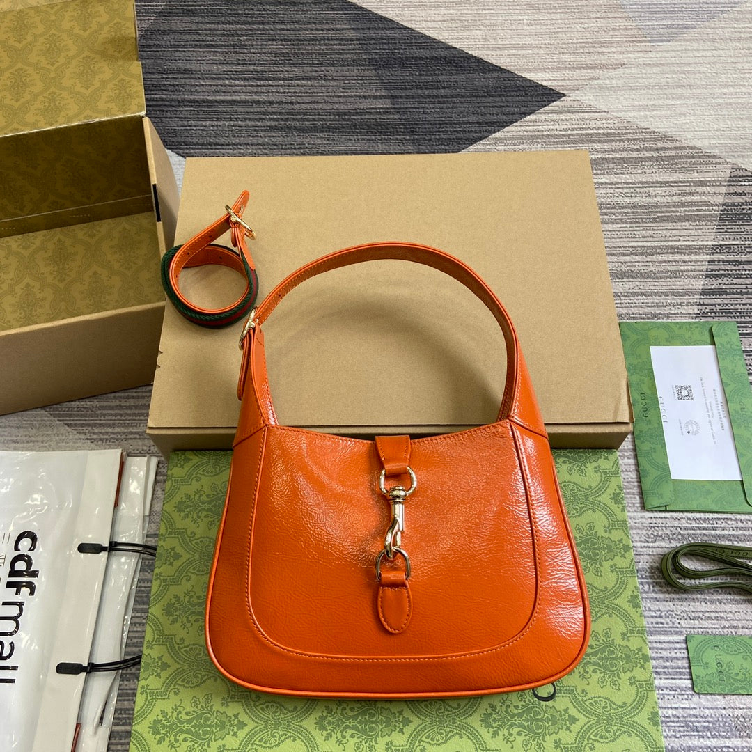 Petit sac bandoulière Jackie 27 en cuir de veau laqué craquelé orange, matériel doré 