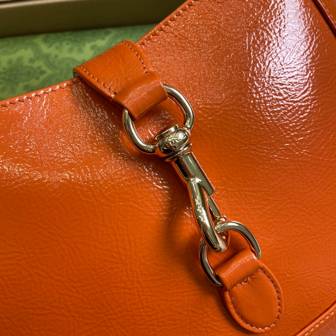 Petit sac bandoulière Jackie 27 en cuir de veau laqué craquelé orange, matériel doré 